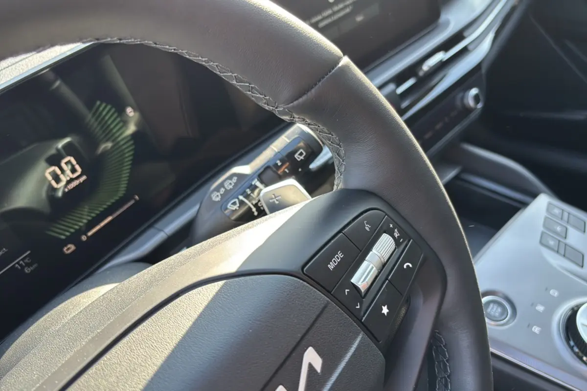 Gros plan sur le volant cuir multifonctions du KIA Sportage gris eclipse, avec tableau de bord numérique en arrière-plan.