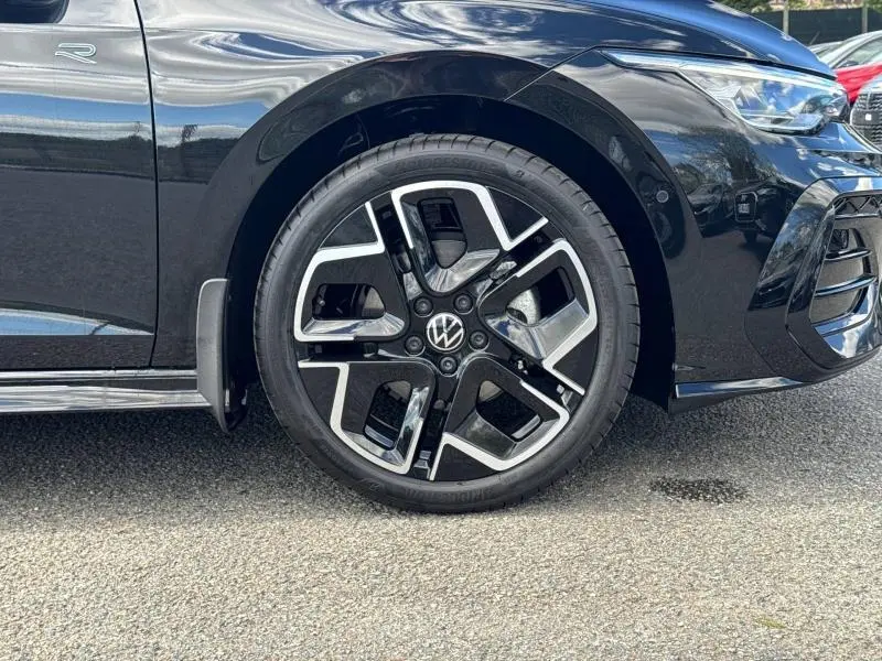 Gros plan sur la roue avant droite noire et jante alu au design moderne d'une Volkswagen Golf 1.5 eTSI R-Line noire Grenadilla.