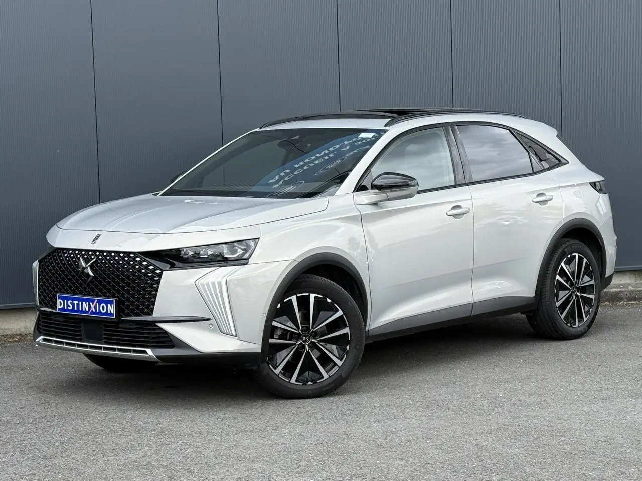 DS7 2025 Cristal Pearl en 3/4 avant droit, avec calandre noire distinctive et jantes alliage 19 pouces.