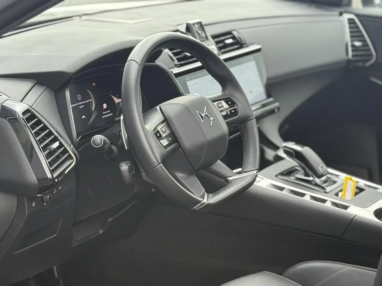 Intérieur noir du DS7 2025 vu côté conducteur, volant cuir avec logo DS et console centrale moderne.