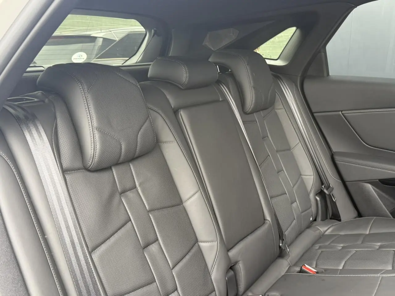 Vue intérieure de la banquette arrière en cuir noir Basalte du DS7 2025, avec ceintures de sécurité visibles.