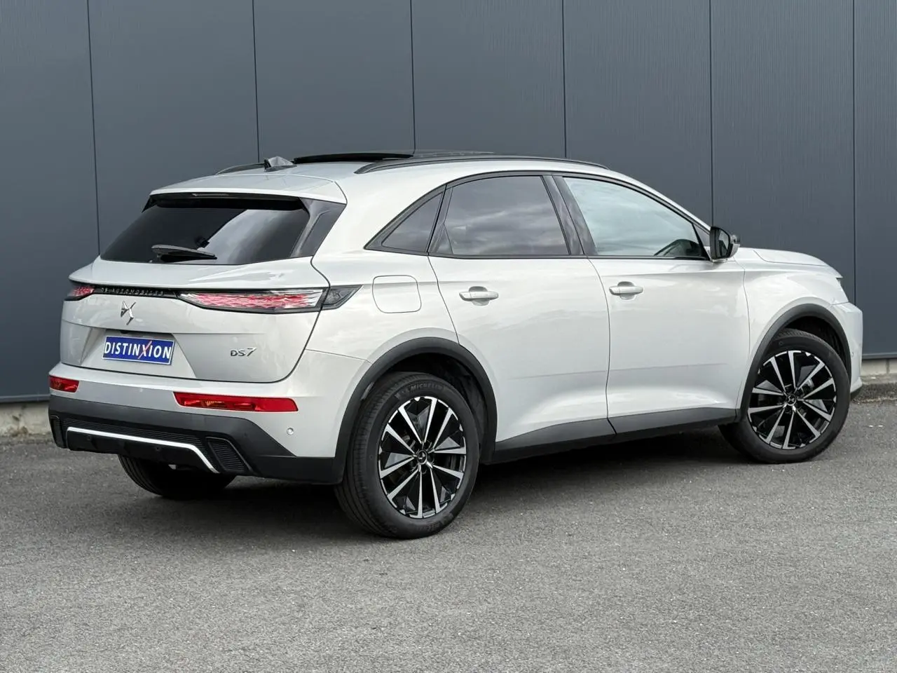 Vue 3/4 arrière droite d'un DS7 Cristal Pearl avec jantes alliage noires et toit ouvrant panoramique.