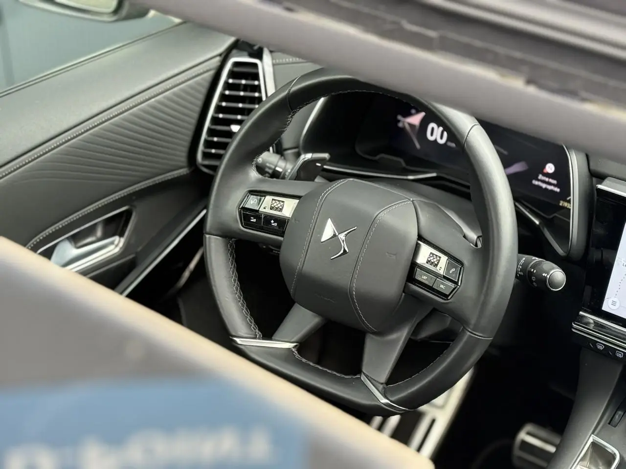Vue rapprochée du volant en cuir noir du DS7 2025, avec tableau de bord numérique et détails de la porte côté gauche.