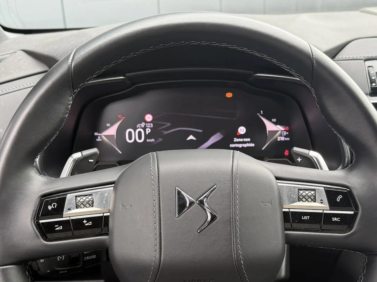Vue rapprochée du volant en cuir noir avec logo DS et combiné numérique affichant la navigation du DS7 2025.