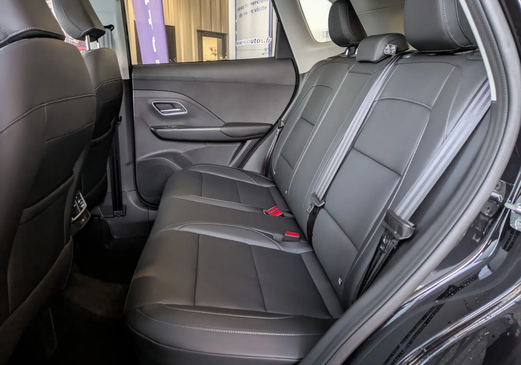 Vue intérieure arrière côté droit du MG ZS 2026 noir, sièges arrière en similicuir noir perforé et ceintures grises.