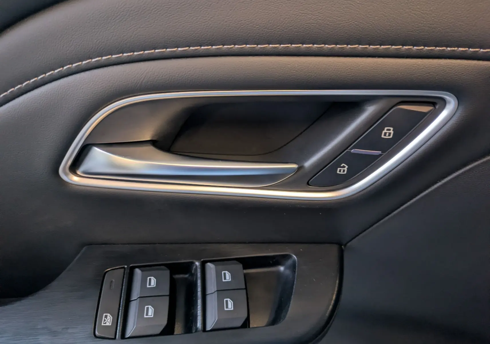 Gros plan sur la poignée intérieure côté gauche noire avec commandes de verrouillage et boutons de lève-vitres du MG ZS 2026.