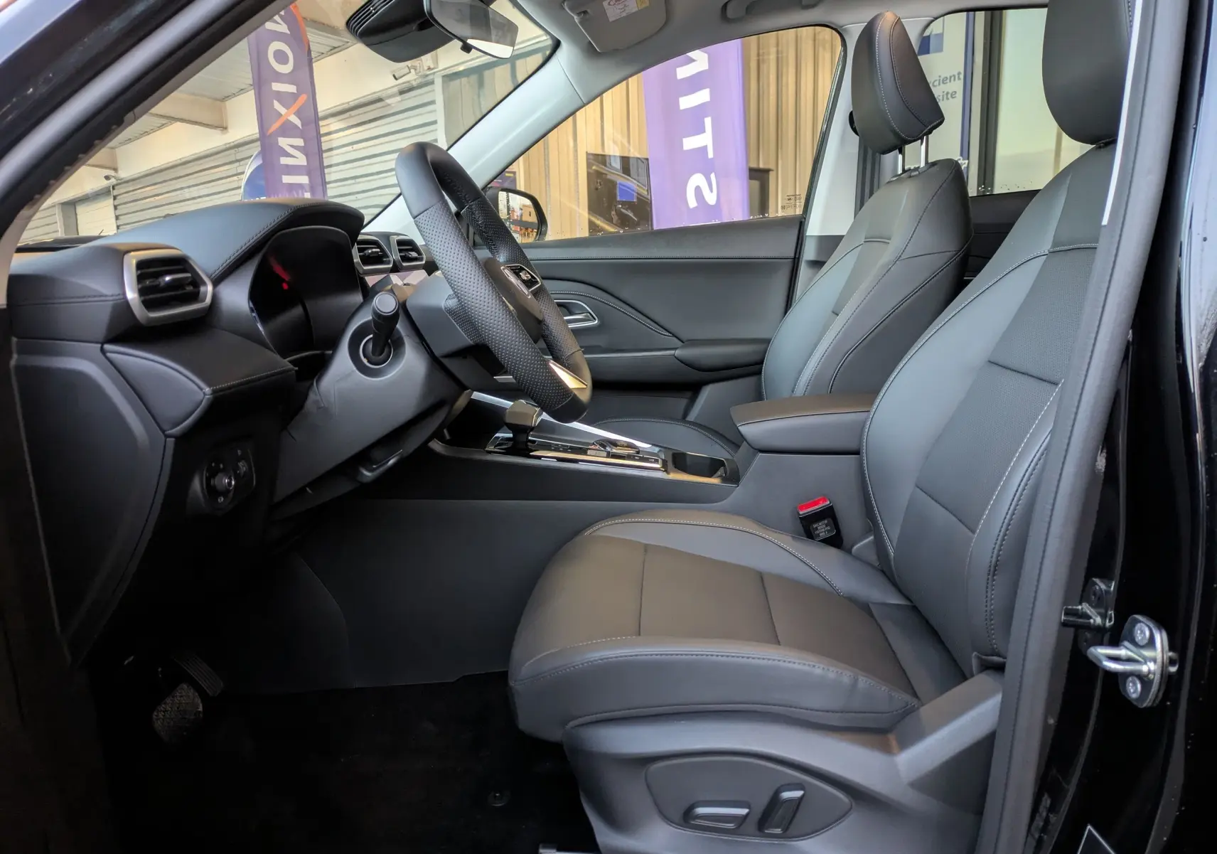 Vue intérieure côté conducteur du MG MOTOR ZS 2026 noir, sièges en similicuir perforé gris et volant cuir chauffant.