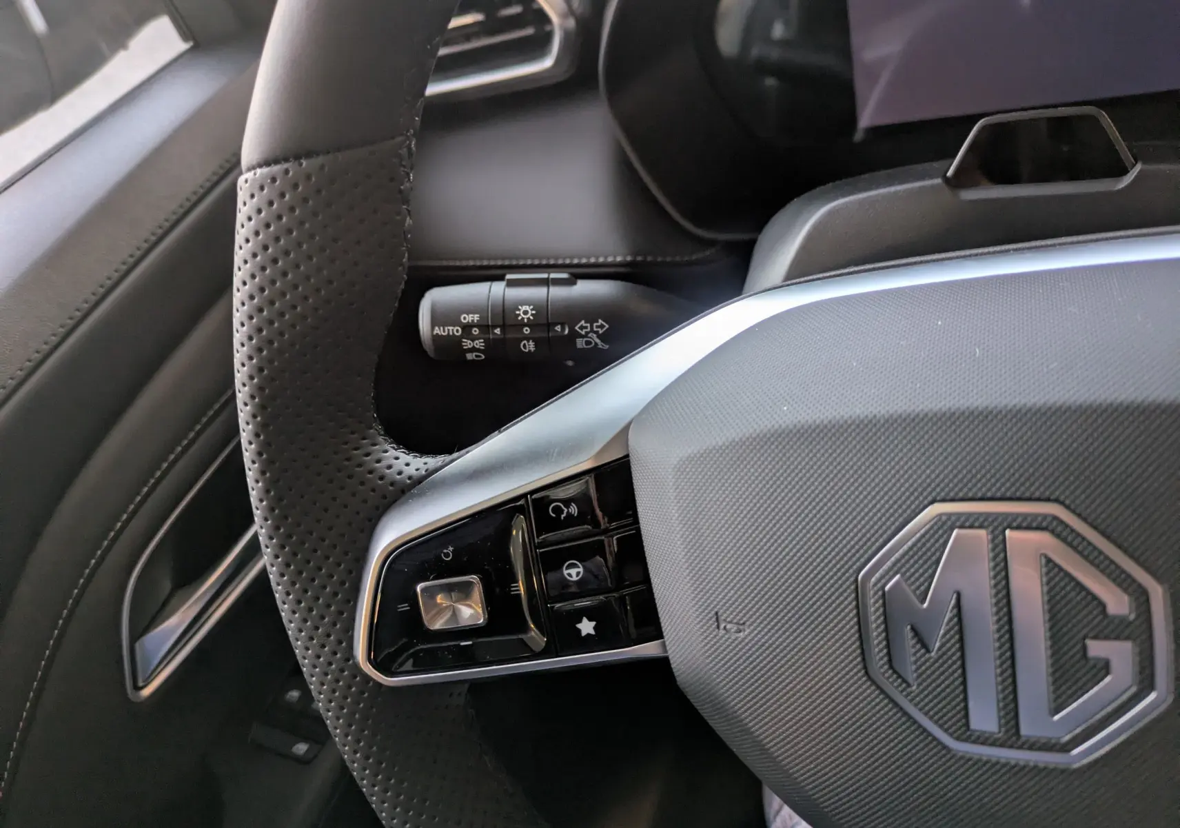 Gros plan sur le volant en cuir noir perforé du MG ZS 2026 avec commandes intégrées et logo MG au centre.