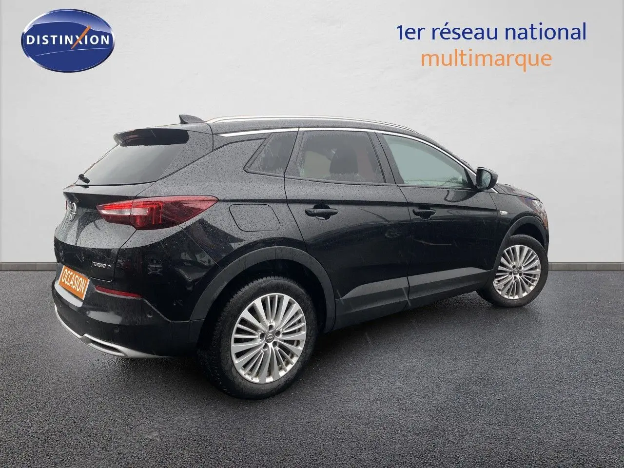 Opel Grandland X noir vue 3/4 arrière côté droit, avec jantes alliage et feux arrière allumés.