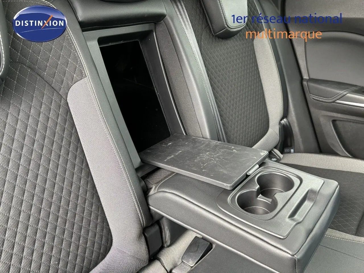 Détail de l'accoudoir central arrière ouvert avec tablette et porte-gobelets sur les sièges tissu gris de l'Opel Grandland X noir.