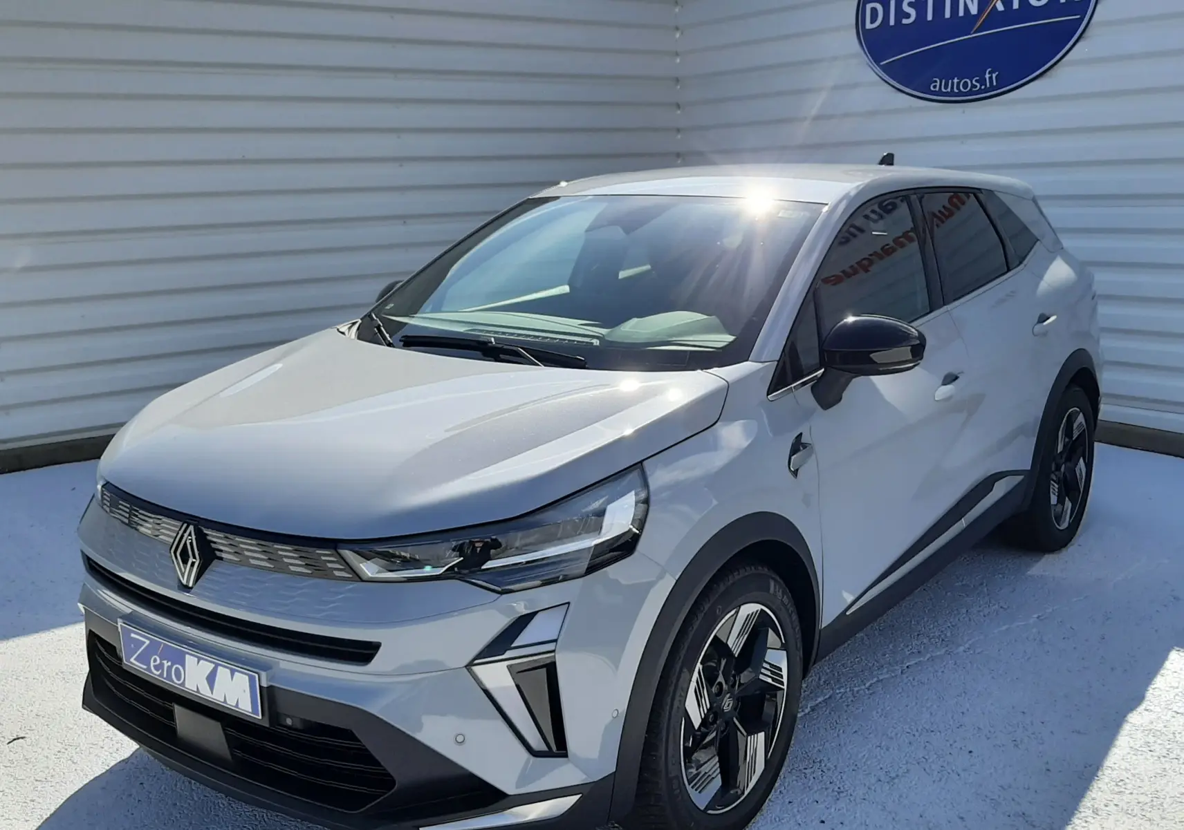 Vue 3/4 avant d'un Renault Symbioz gris rafale avec jantes biton et calandre moderne sous un ciel ensoleillé.