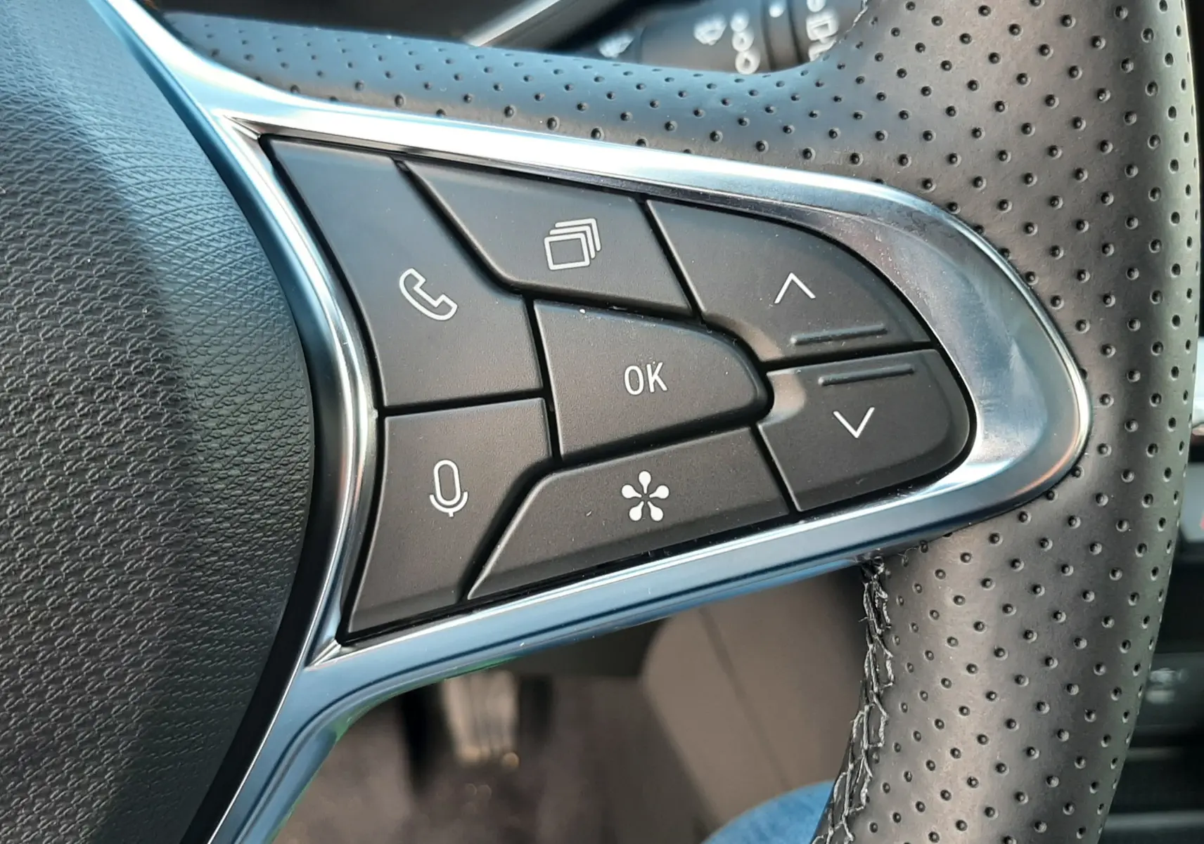 Gros plan sur les commandes multifonctions à droite du volant perforé du Renault Symbioz gris Rafale 2024.