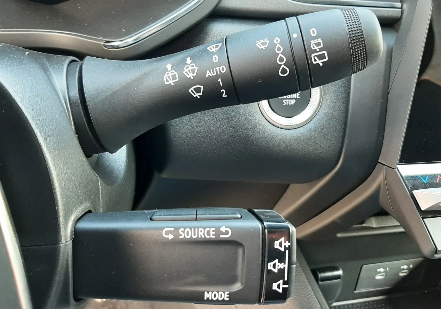 Gros plan sur les commandes au volant du Renault Symbioz gris Rafale, avec bouton start/stop et leviers multifonctions.