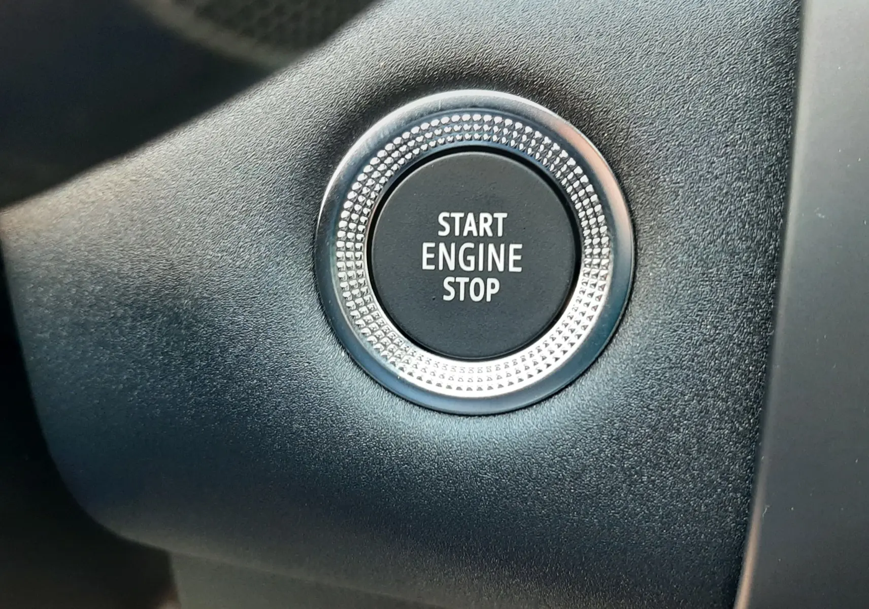 Bouton démarrage moteur circulaire en gros plan sur tableau de bord noir du Renault Symbioz gris Rafale 2024 hybride.