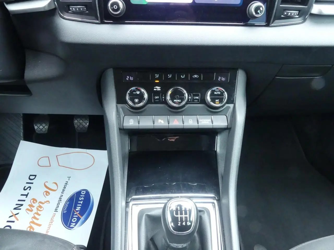 Vue rapprochée de la console centrale noire du Skoda Karoq blanc 2024, avec levier de vitesses manuel et commandes climatisation.