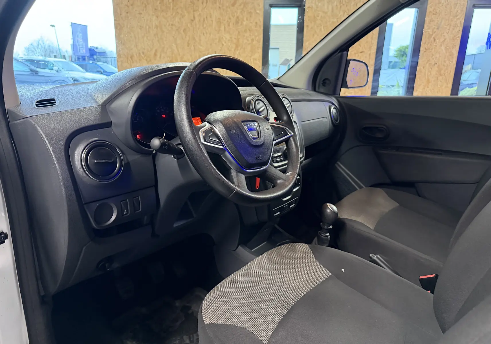 Intérieur du Dacia Dokker 2019 vu côté conducteur, volant multifonctions et sellerie grise avec détails noirs.