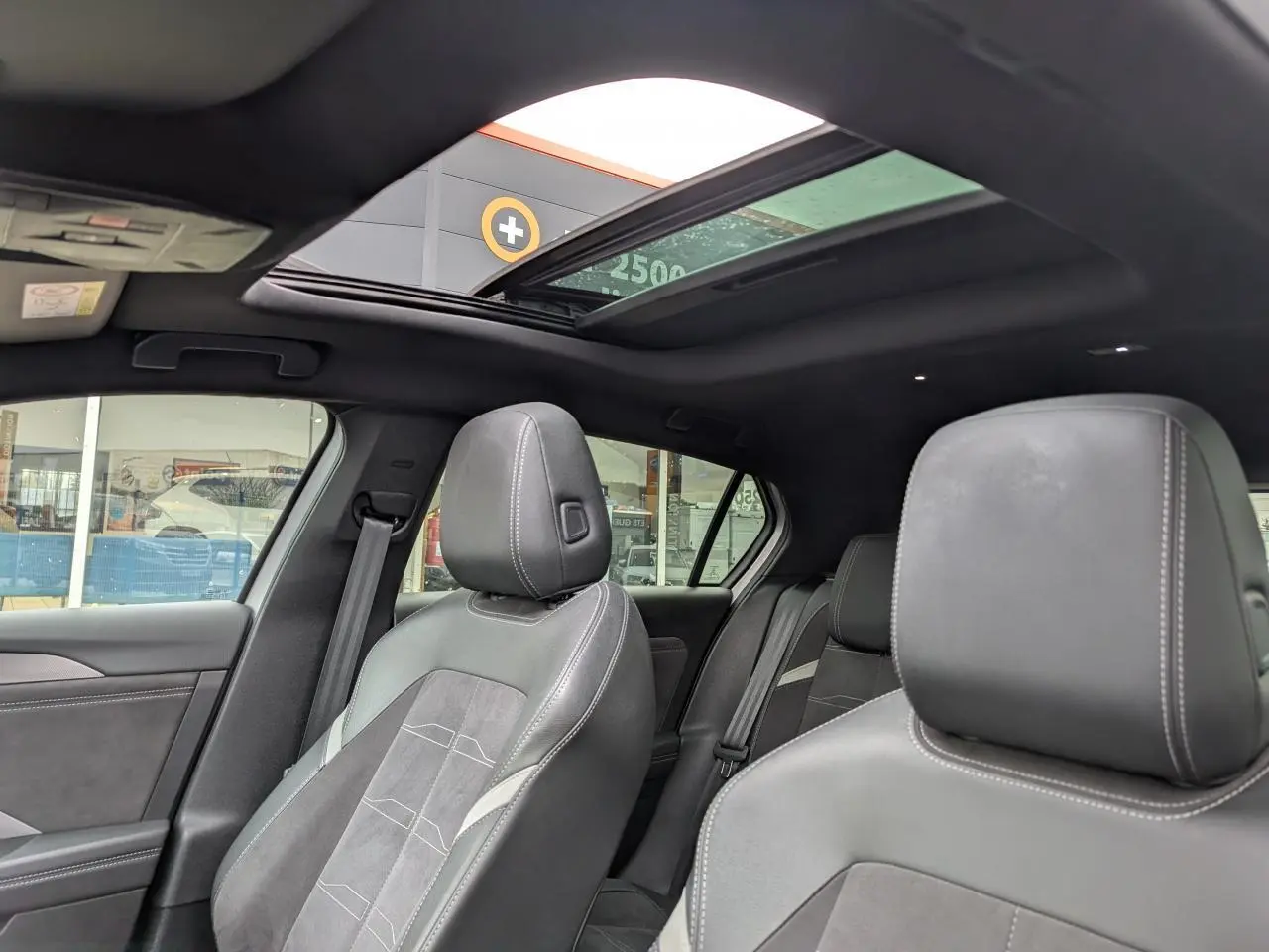 Vue intérieure de l’Opel Astra 2024, sièges avant en cuir gris avec surpiqûres blanches et toit ouvrant panoramique.