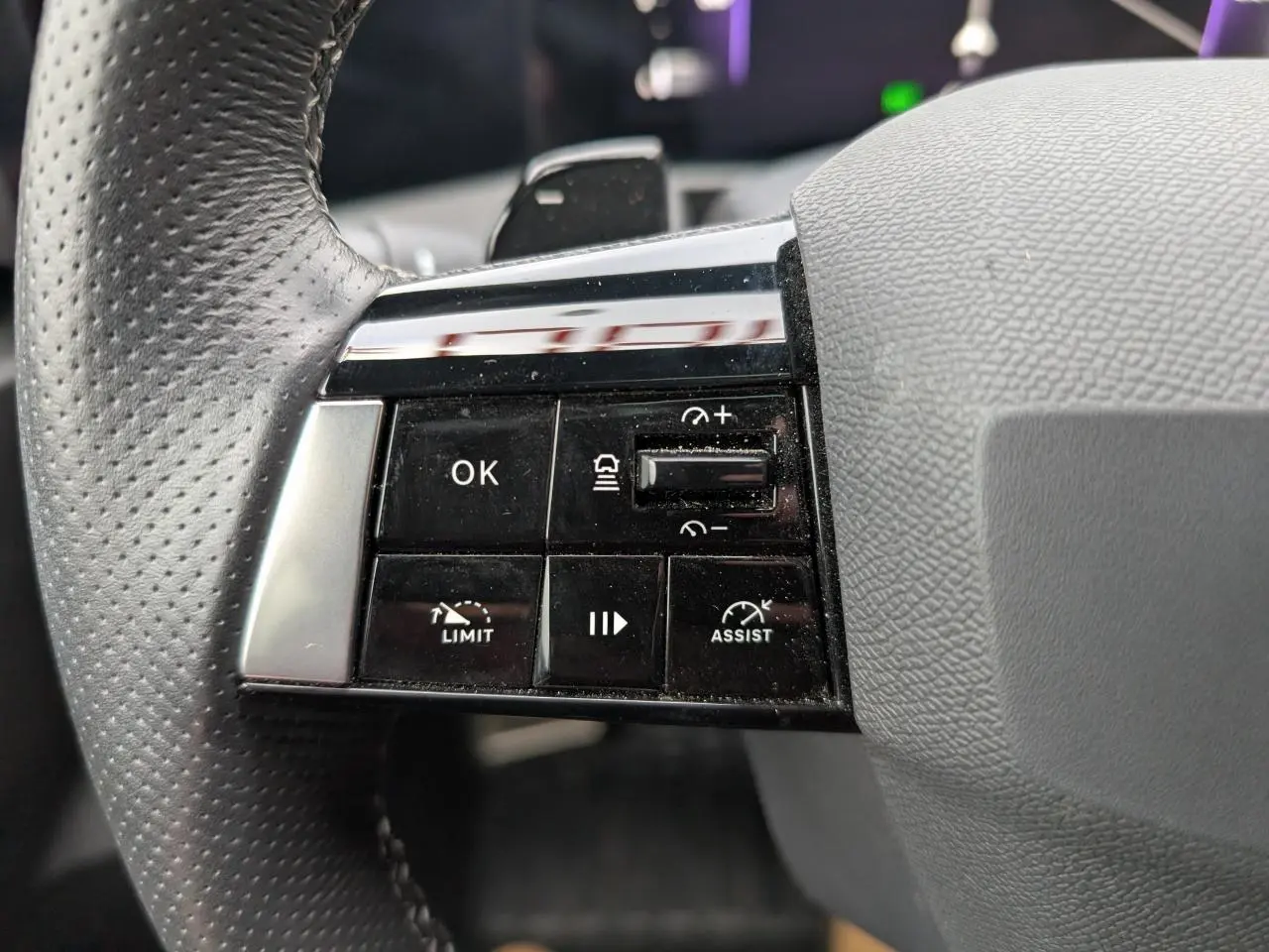 Gros plan sur les commandes à gauche du volant en cuir perforé de l'Opel Astra 2024 gris métallisé, version Ultimate.