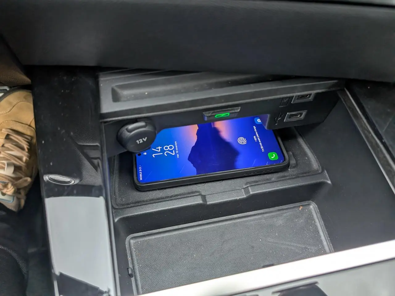 Vue rapprochée de la console centrale de l’Opel Astra 2024 gris métallisé, avec un smartphone posé sur le chargeur sans fil.