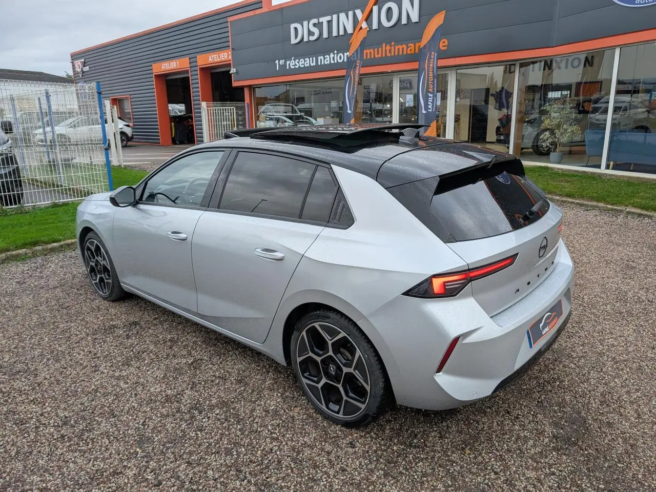 Opel Astra 2024 gris métallisé vue 3/4 arrière droit avec toit noir et jantes distinctives en alliage.