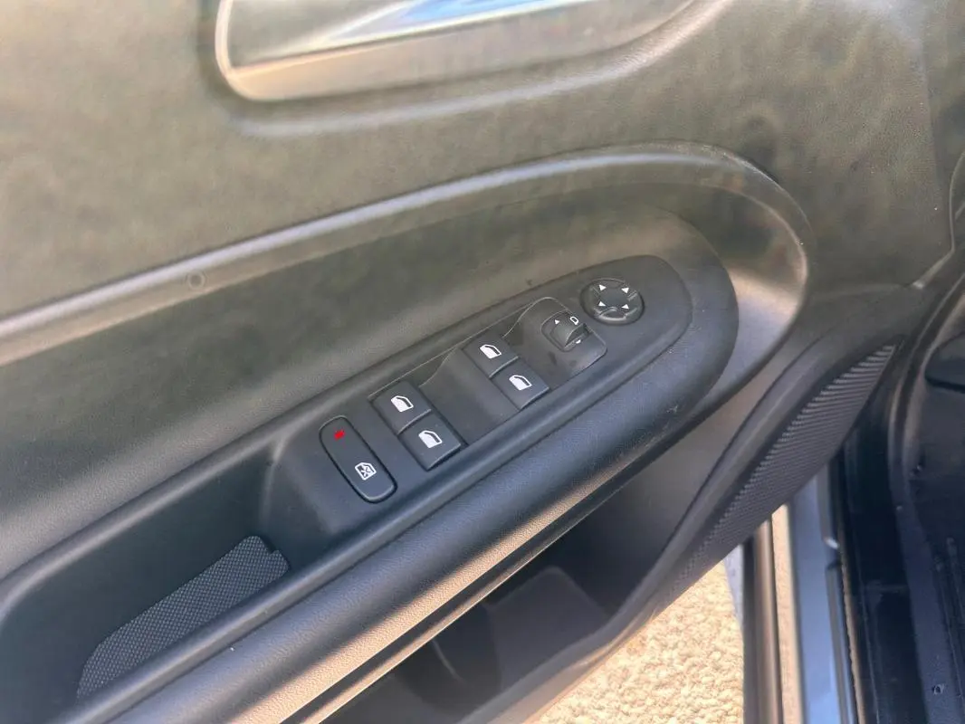 Vue rapprochée du panneau de commandes des vitres électriques côté conducteur du Jeep Avenger gris foncé 2025.