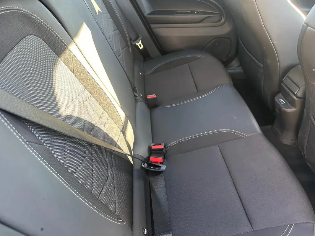 Vue intérieure des sièges arrière gris foncé du Jeep Avenger 2025 avec ceintures de sécurité visibles.