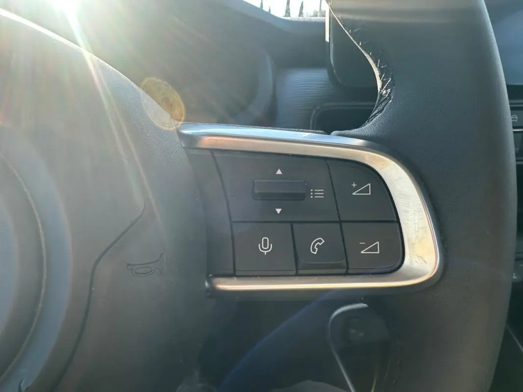 Gros plan sur les commandes à droite du volant cuir du Jeep Avenger gris foncé, avec lumière naturelle.