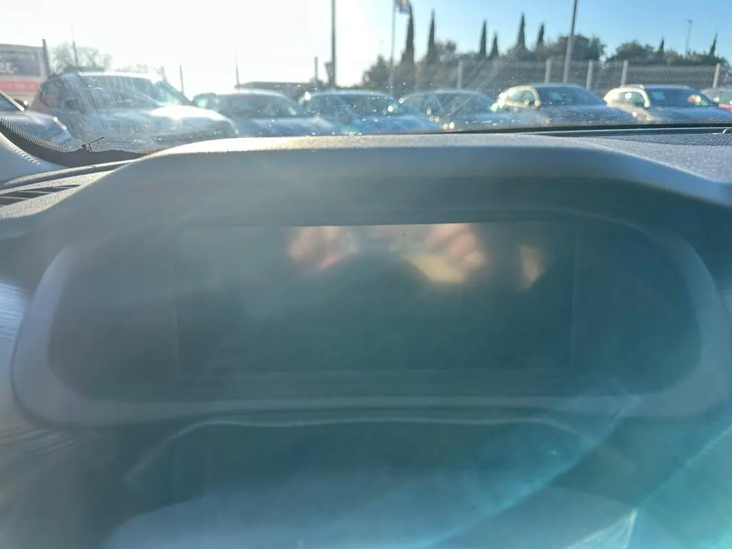 Vue intérieure du tableau de bord du Jeep Avenger 2025, écran central éteint avec reflet du soleil.