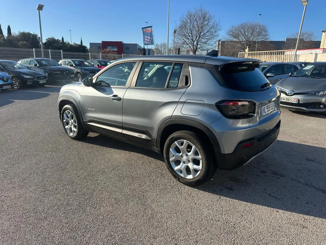 Vue 3/4 arrière droite d'un Jeep Avenger gris foncé avec jantes alliage 17 pouces, dans un parking extérieur.
