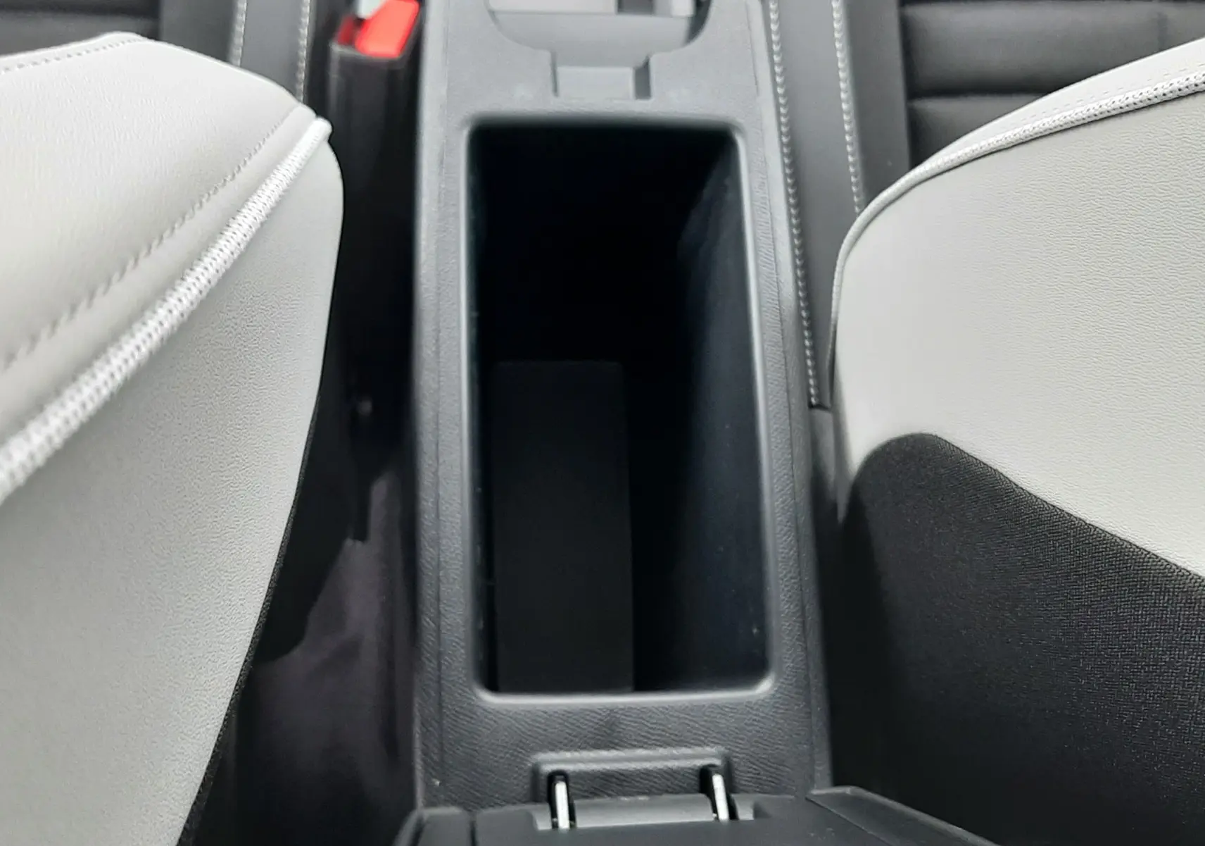 Vue plongeante sur la console centrale noire entre les sièges avant gris clair du Citroën C3 Aircross hybride 2025.