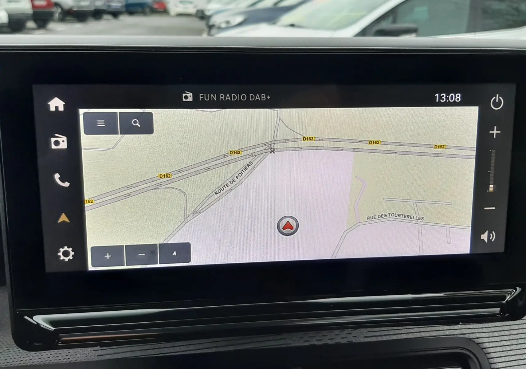 Écran tactile central du Citroën C3 Aircross hybride 2025, vue intérieure avec navigation affichée, arrière-plan parking.