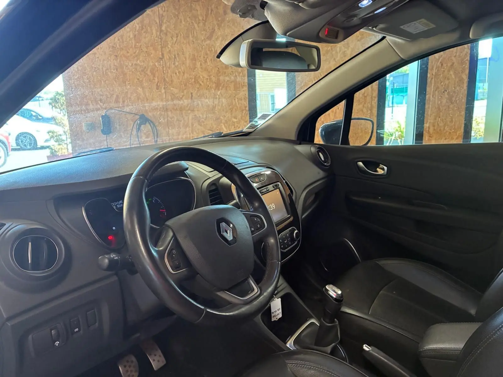Vue intérieure côté conducteur du Renault Captur bleu 2017, volant multifonction et levier de vitesse manuel visibles.