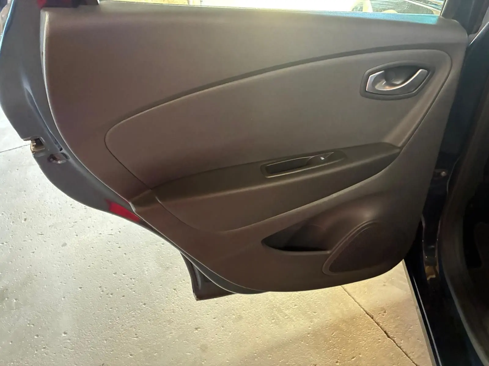 Vue intérieure de la porte arrière droite d’un Renault Captur bleu 2017, panneau noir avec commande de vitre électrique.
