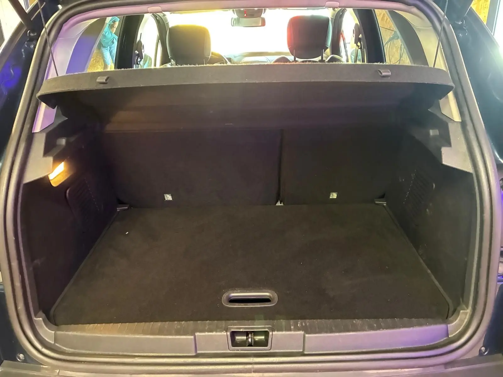 Coffre ouvert vu de l'arrière d'un Renault Captur bleu 2017, montrant un espace de chargement vide et propre.