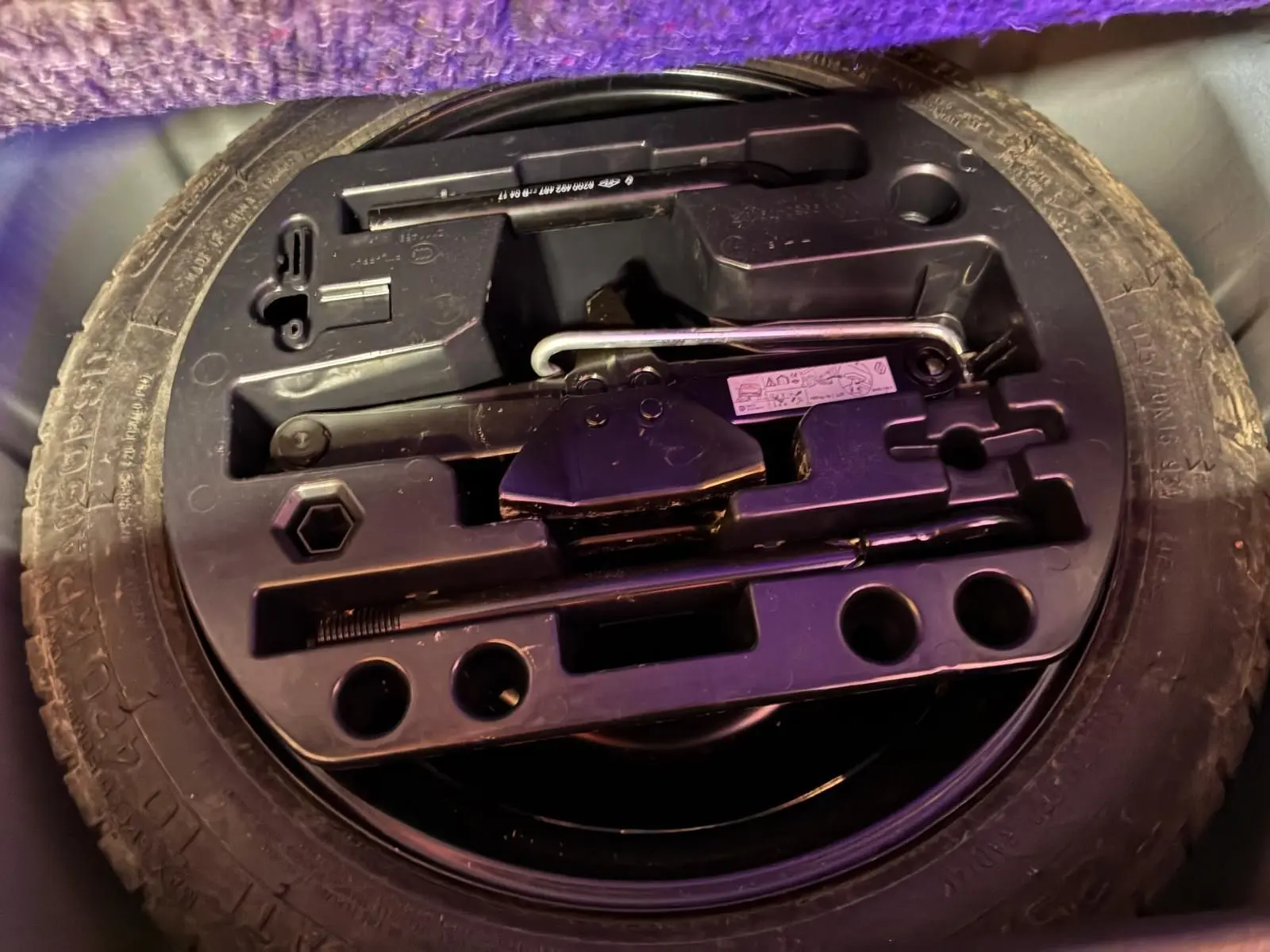 Gros plan sur la roue de secours et le kit d'outils dans le coffre d'un Renault Captur bleu 2017.