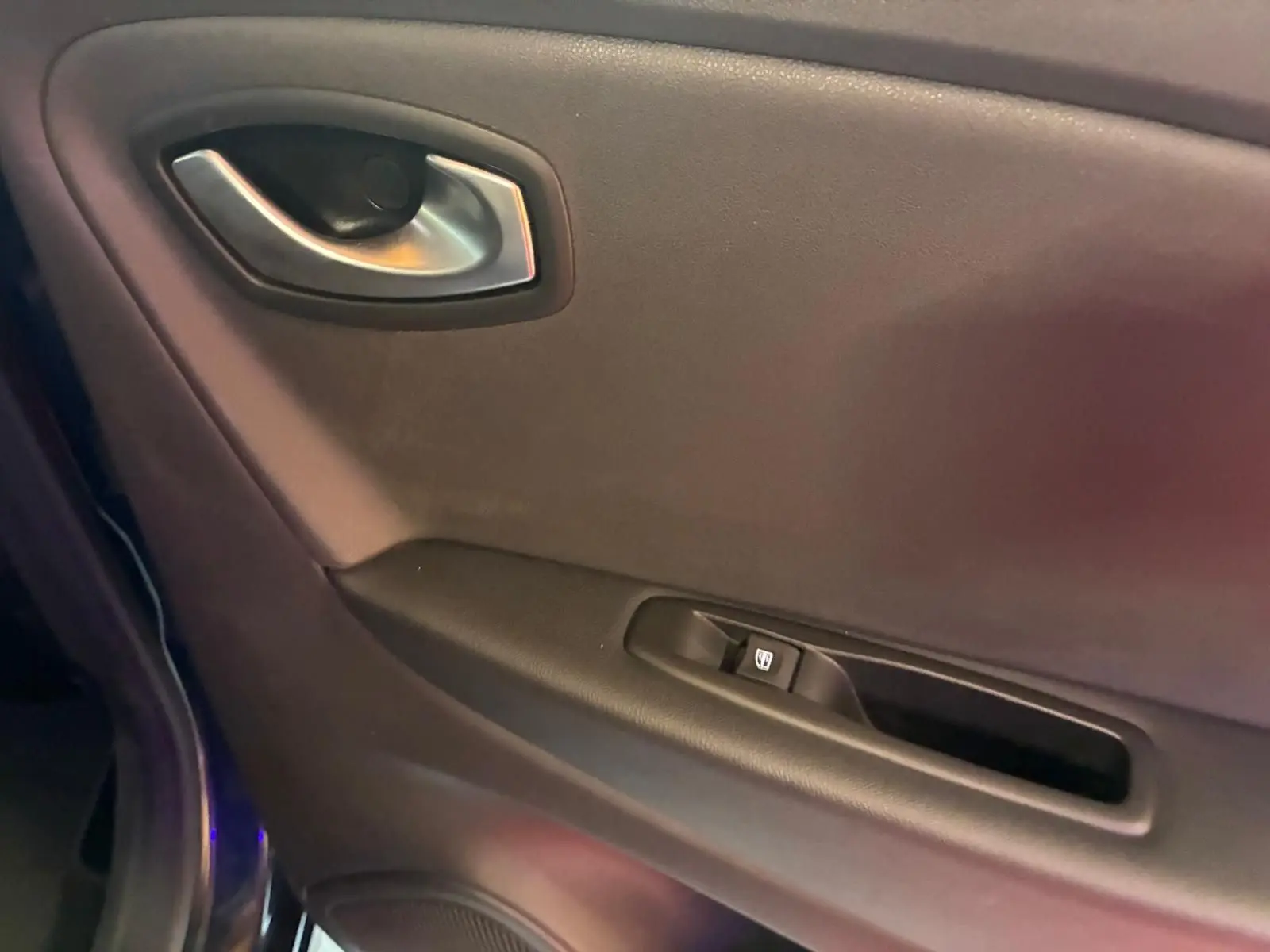 Gros plan sur la poignée intérieure et commande de vitre côté gauche d'une Renault Captur bleu 2017.