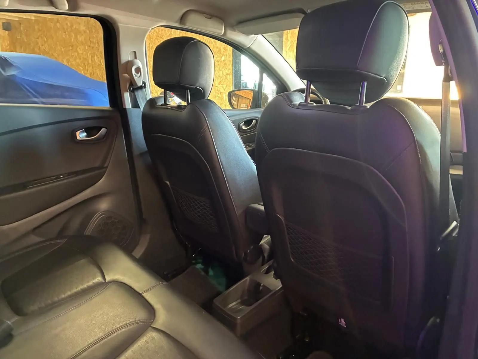 Vue intérieure arrière du Renault Captur 1.5 DCI 90 Intens 2017, sièges avant en cuir noir et banquette arrière en tissu.