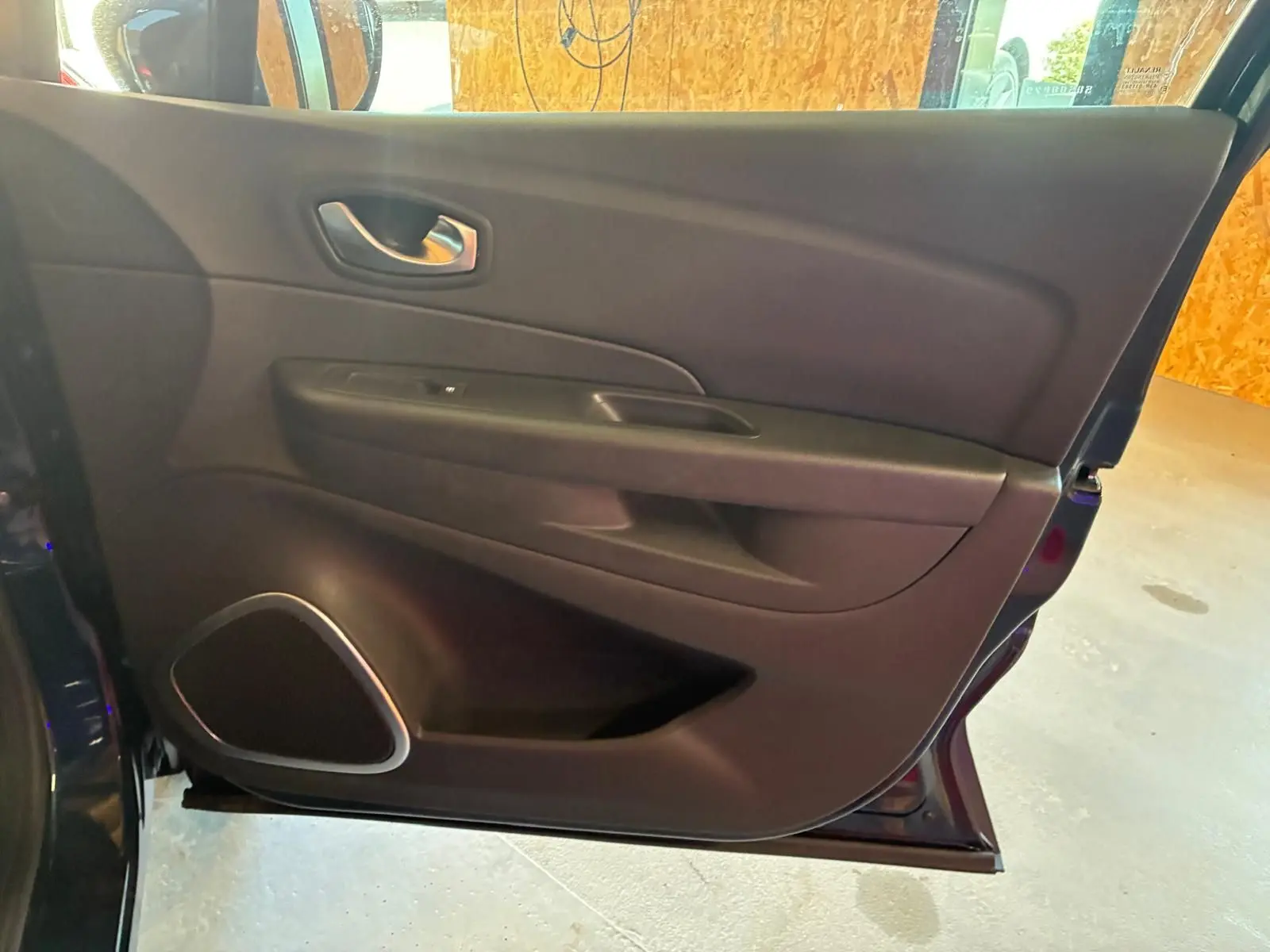 Vue intérieure de la porte avant gauche du Renault Captur bleu, avec poignée argentée et haut-parleur intégré.