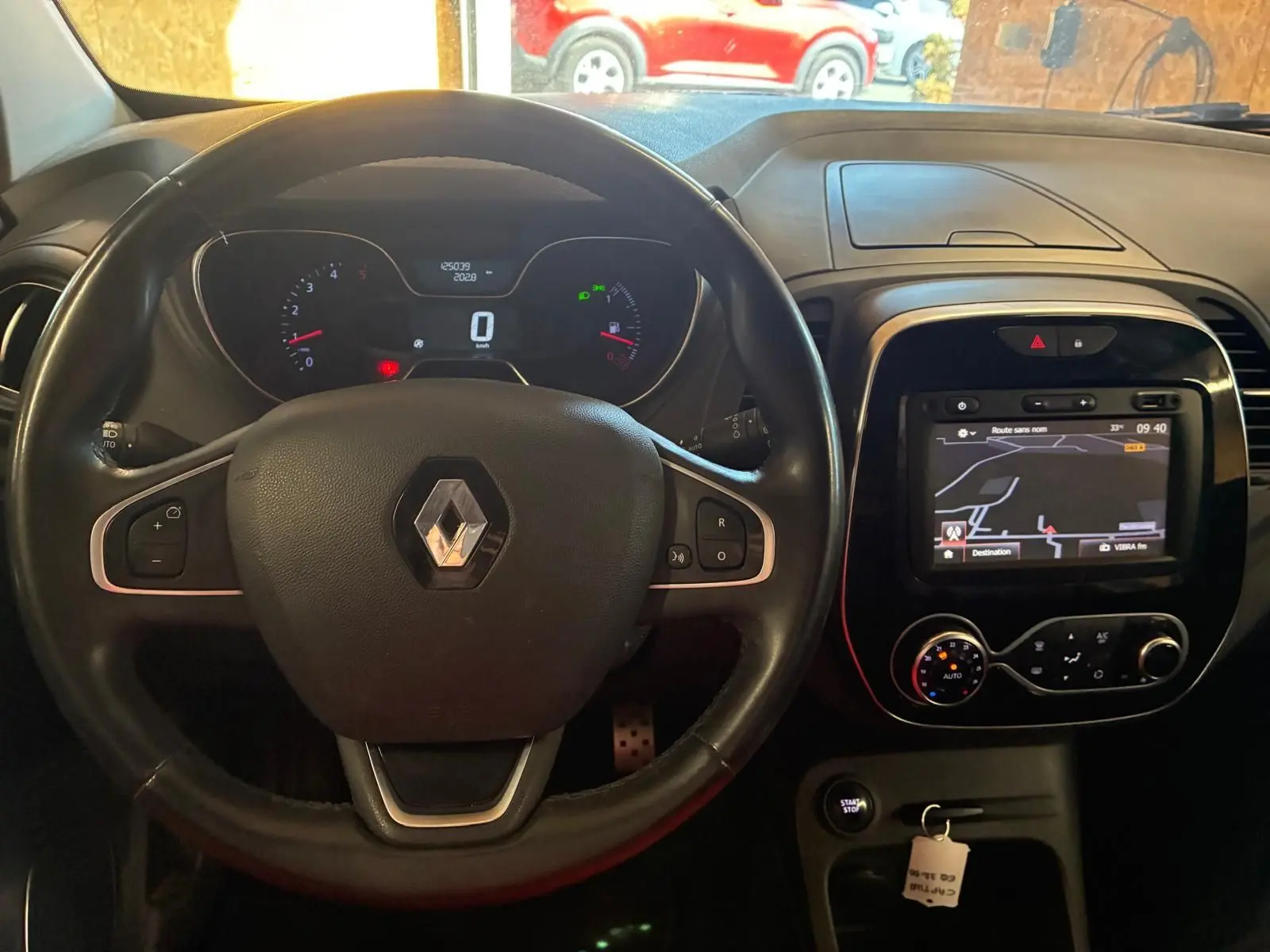 Vue intérieure centrée sur le volant noir Renault Captur 1.5 DCI 90 Intens avec tableau de bord et écran GPS allumé.