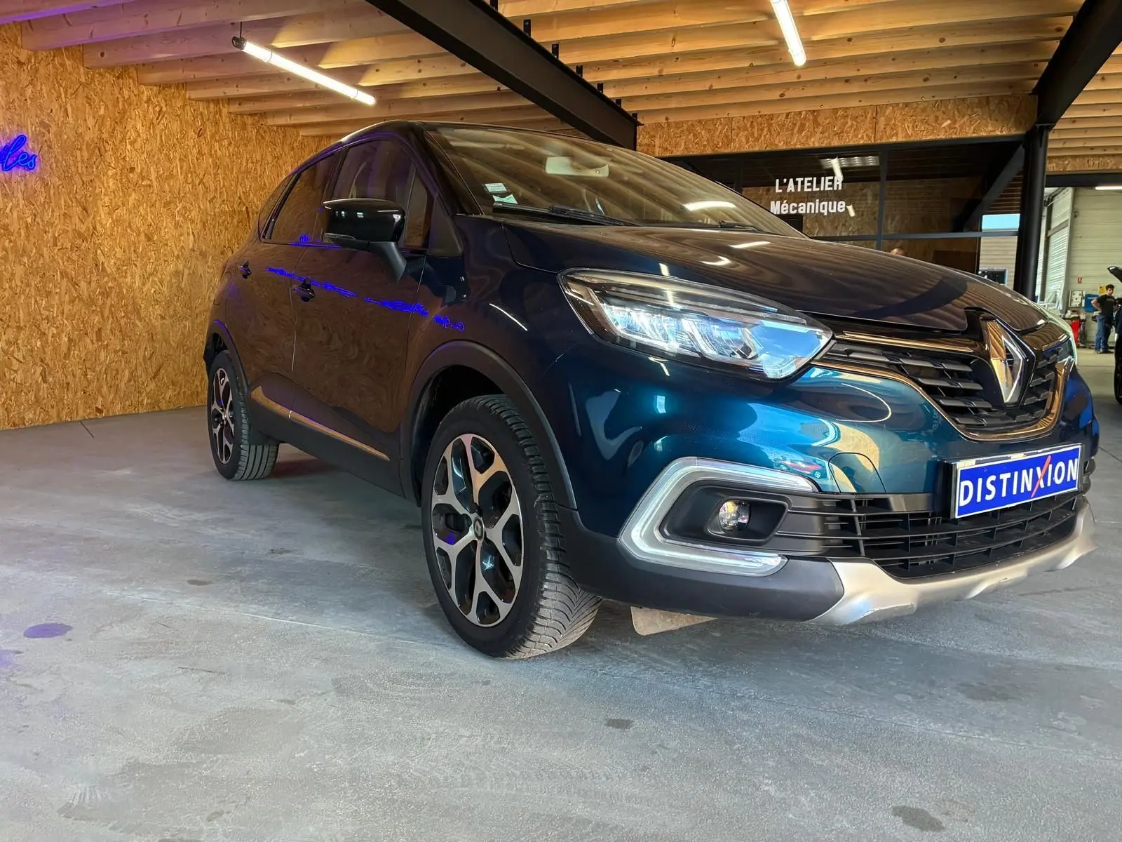 Renault Captur bleu 3/4 avant droit, mettant en valeur ses optiques LED et la calandre distinctive.