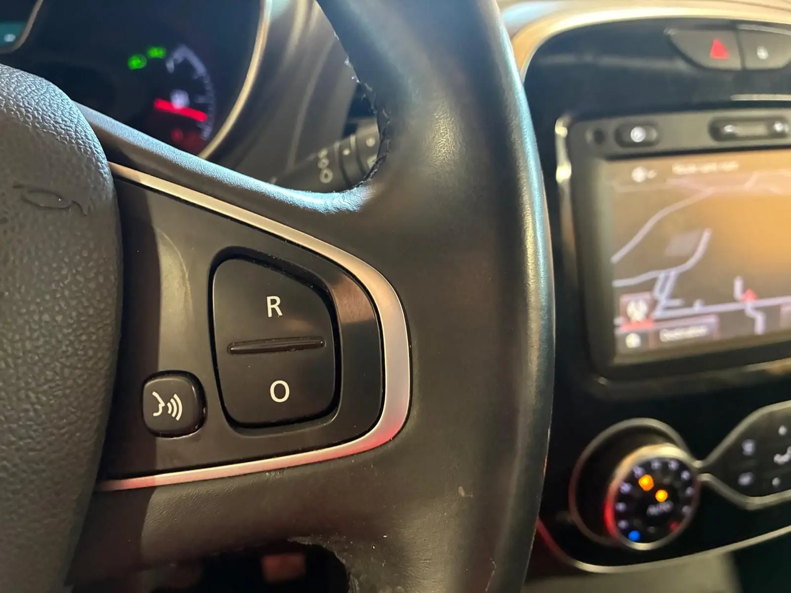 Gros plan sur le volant noir de la Renault Captur 1.5 DCI 90 Intens avec commandes vocales et écran GPS en arrière-plan.