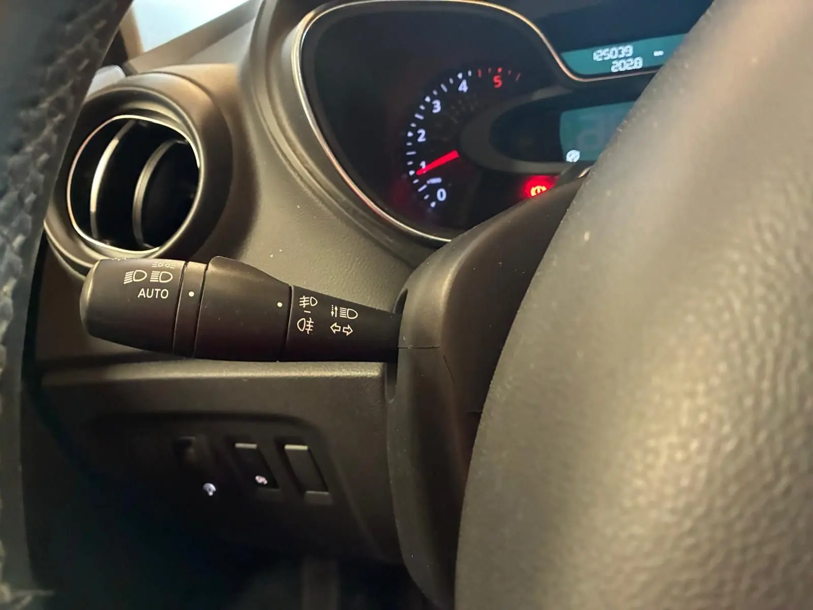 Gros plan sur la commande des phares et clignotants à gauche du volant du Renault Captur bleu, tableau de bord en arrière-plan.