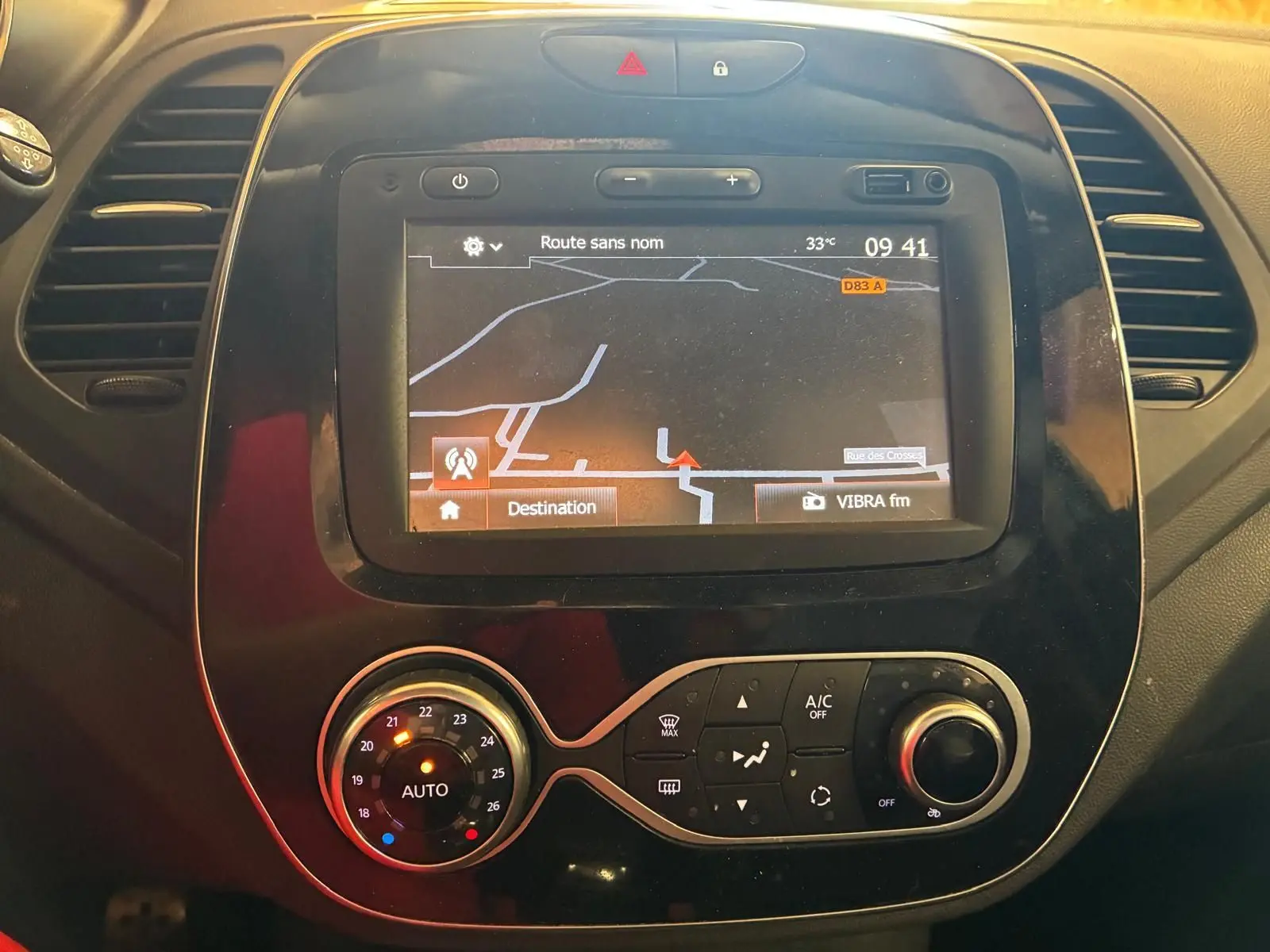 Vue rapprochée du tableau de bord noir du Renault Captur 2017 avec écran GPS et commandes de climatisation.