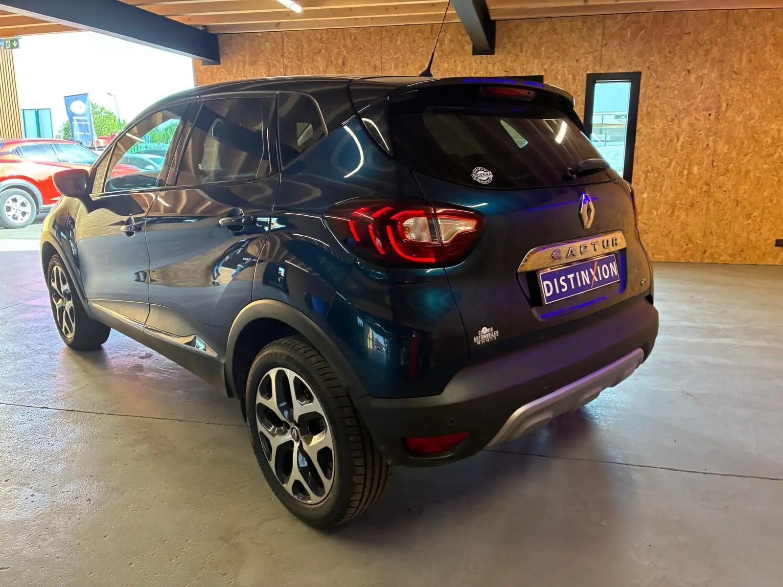 Renault Captur bleu 2017 en 3/4 arrière droit, avec feux arrière allumés et jantes alliage visibles.