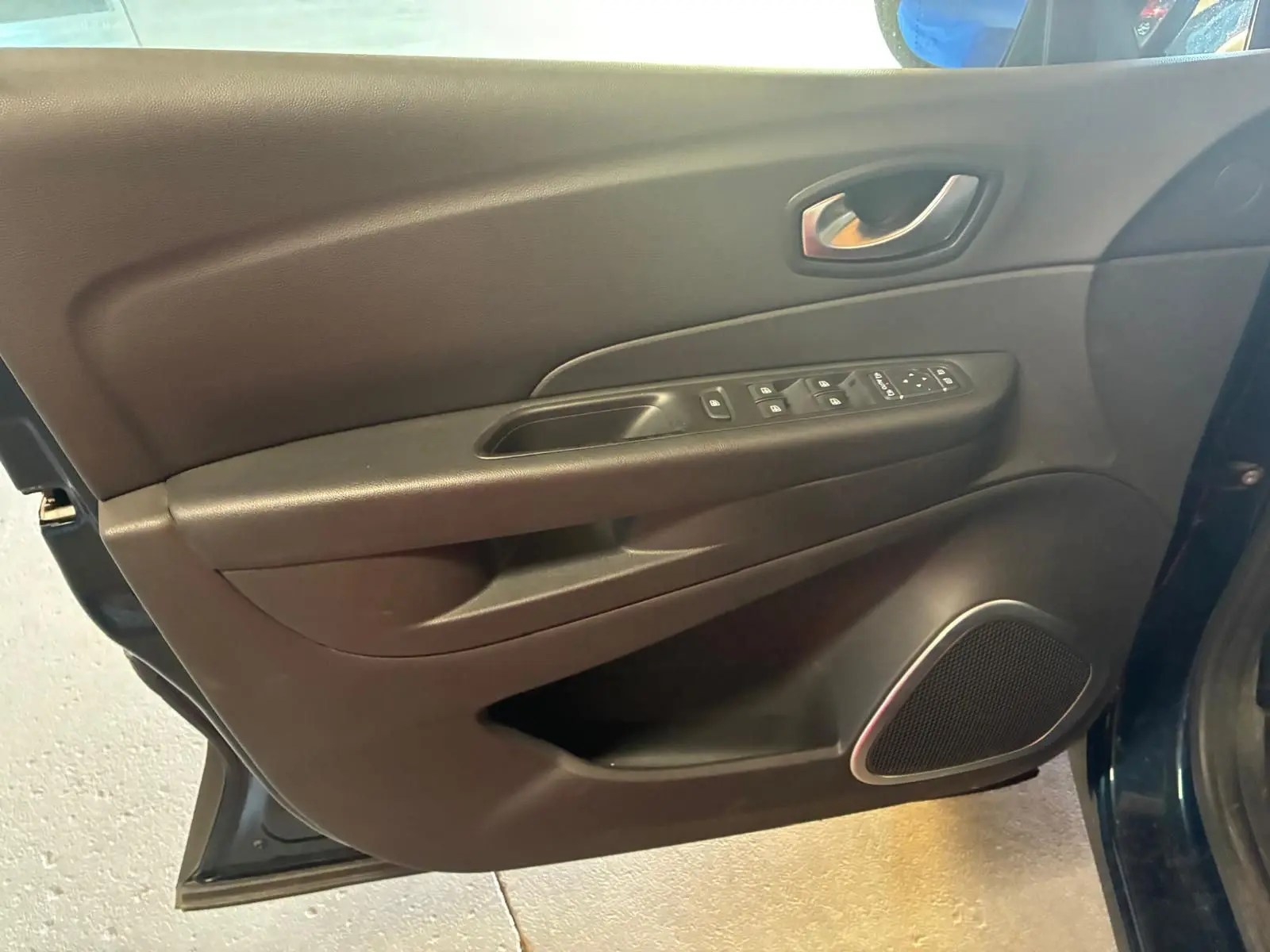 Vue rapprochée de la porte avant gauche du Renault Captur bleu 2017, avec commandes de vitres et haut-parleur intégré.