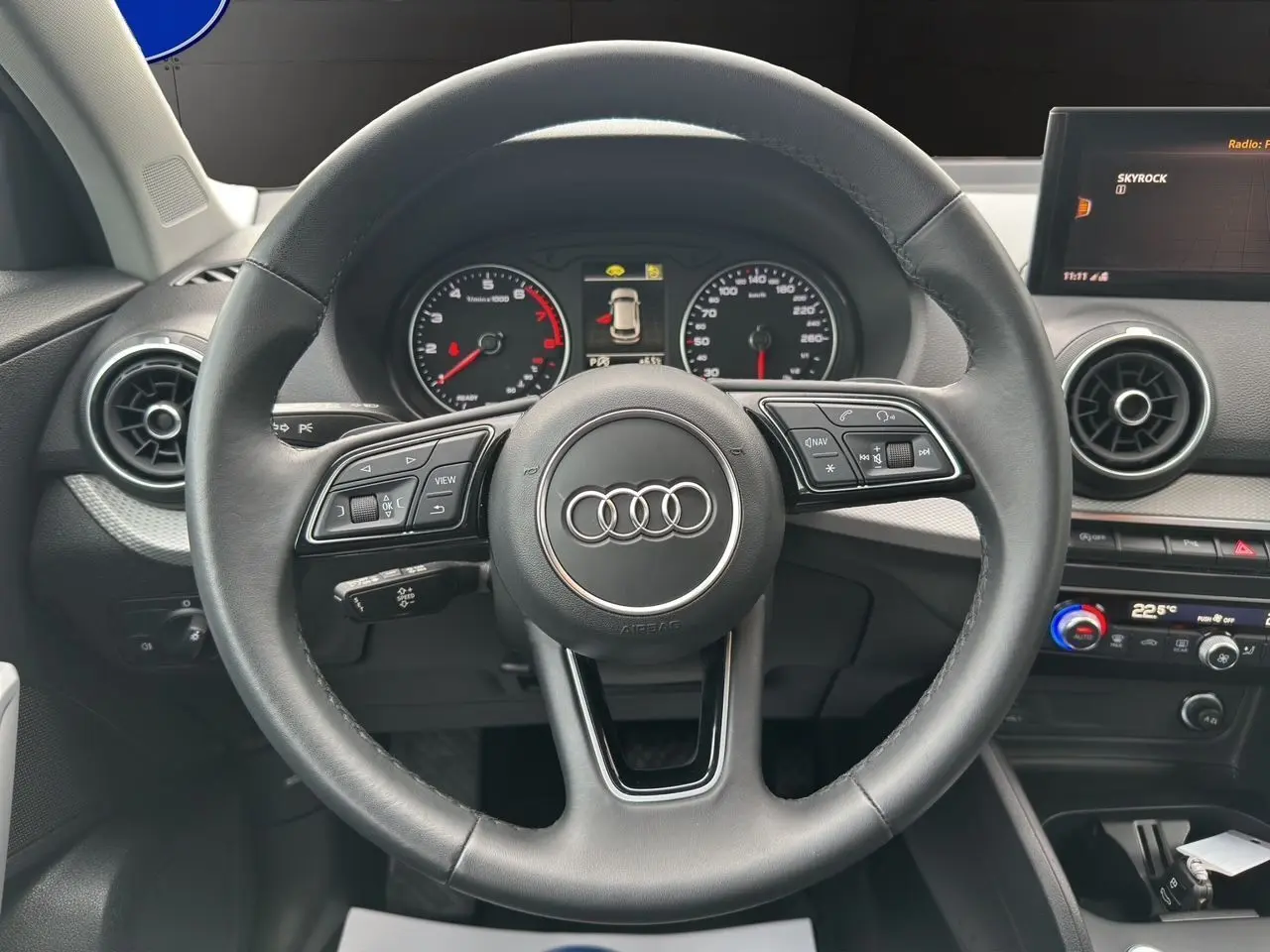 Vue intérieure centrée sur le volant Audi Q2 35 TFSI 2023 avec tableau de bord et écran multimédia visibles.