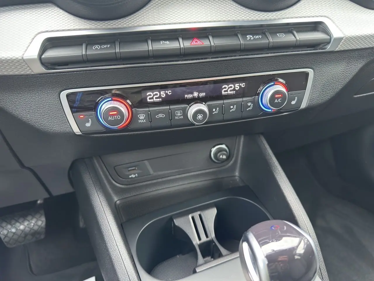 Vue rapprochée de la console centrale de l'Audi Q2 35 TFSI noir mito, montrant la climatisation automatique et le levier de vitesse.