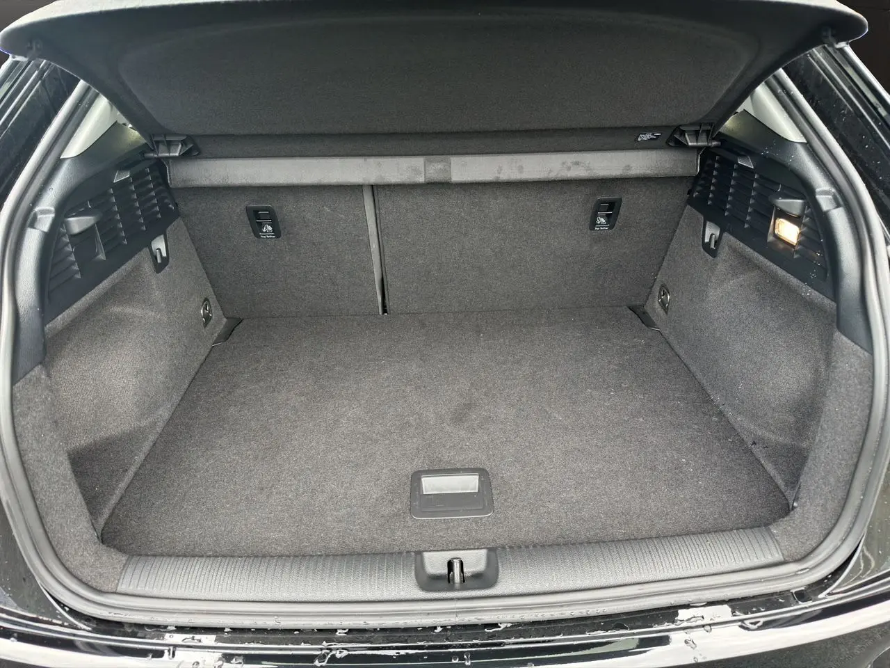 Coffre ouvert d'un Audi Q2 noir Mito, vue intérieure montrant un espace de chargement propre et bien fini.