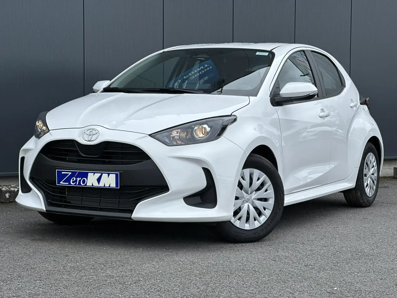 Toyota Yaris hybride blanc pur vue 3/4 avant droit avec calandre noire et jantes acier à enjoliveurs.