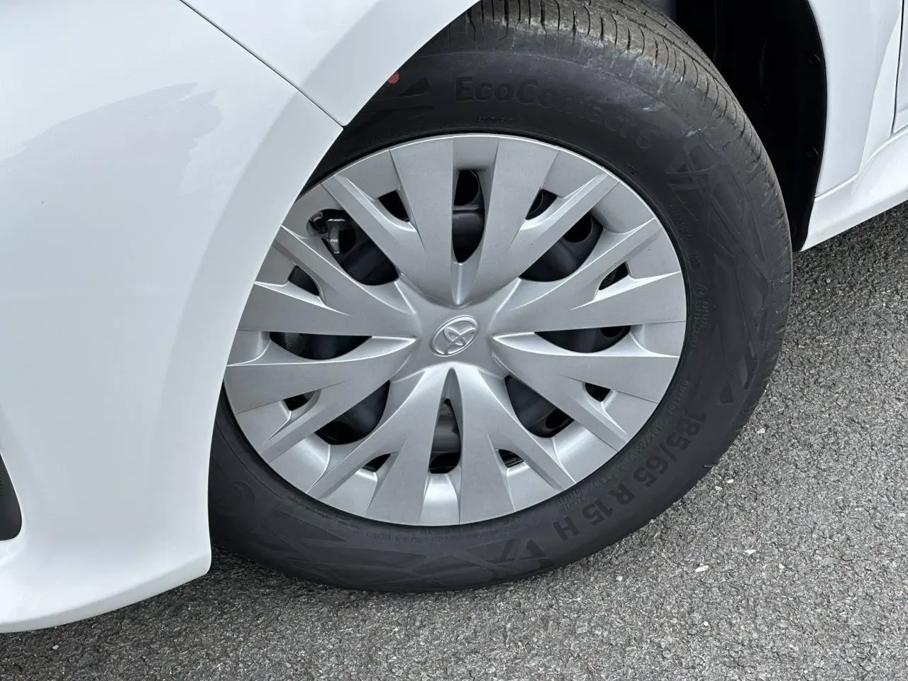 Gros plan sur la roue avant gauche d'une Toyota Yaris blanche Pure, avec enjoliveur gris et pneu EcoContact 6.